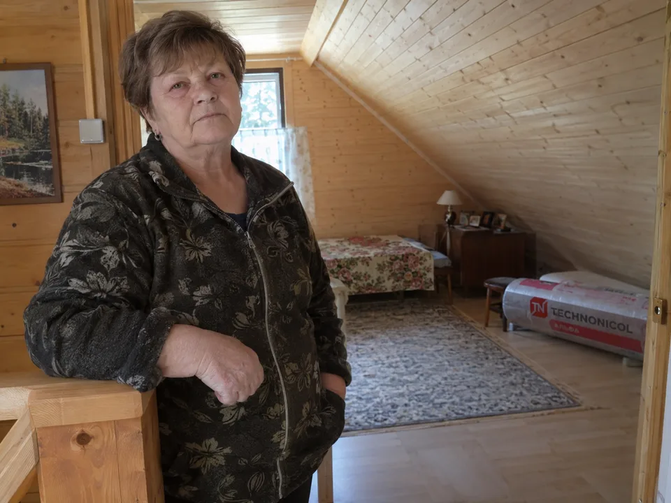 Женщина в спальне мансардного этажа с деревянной отделкой